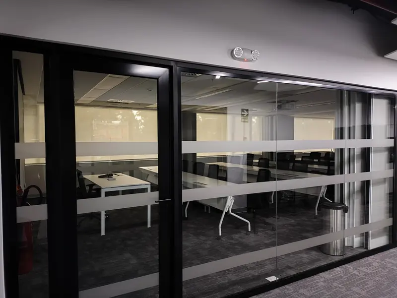 Divisiones de oficina en vidrio templado con perfilería negra y vinil de privacidad