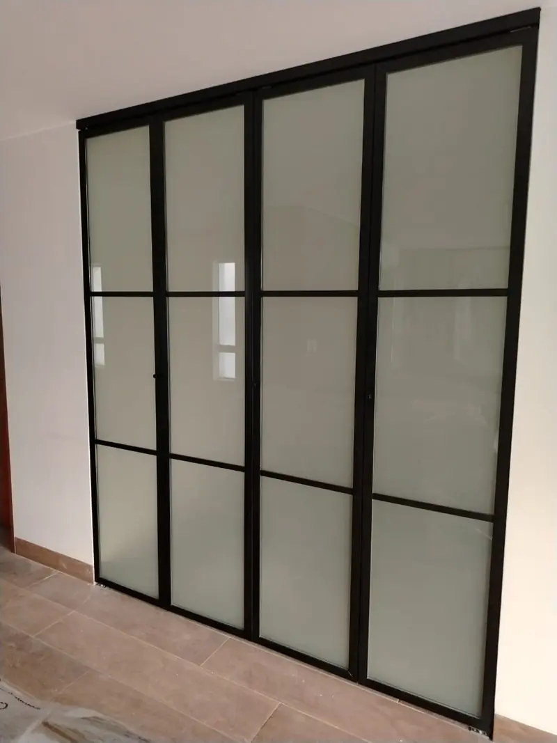 Puerta corrediza estilo industrial en vidrio esmerilado con retícula de aluminio negro